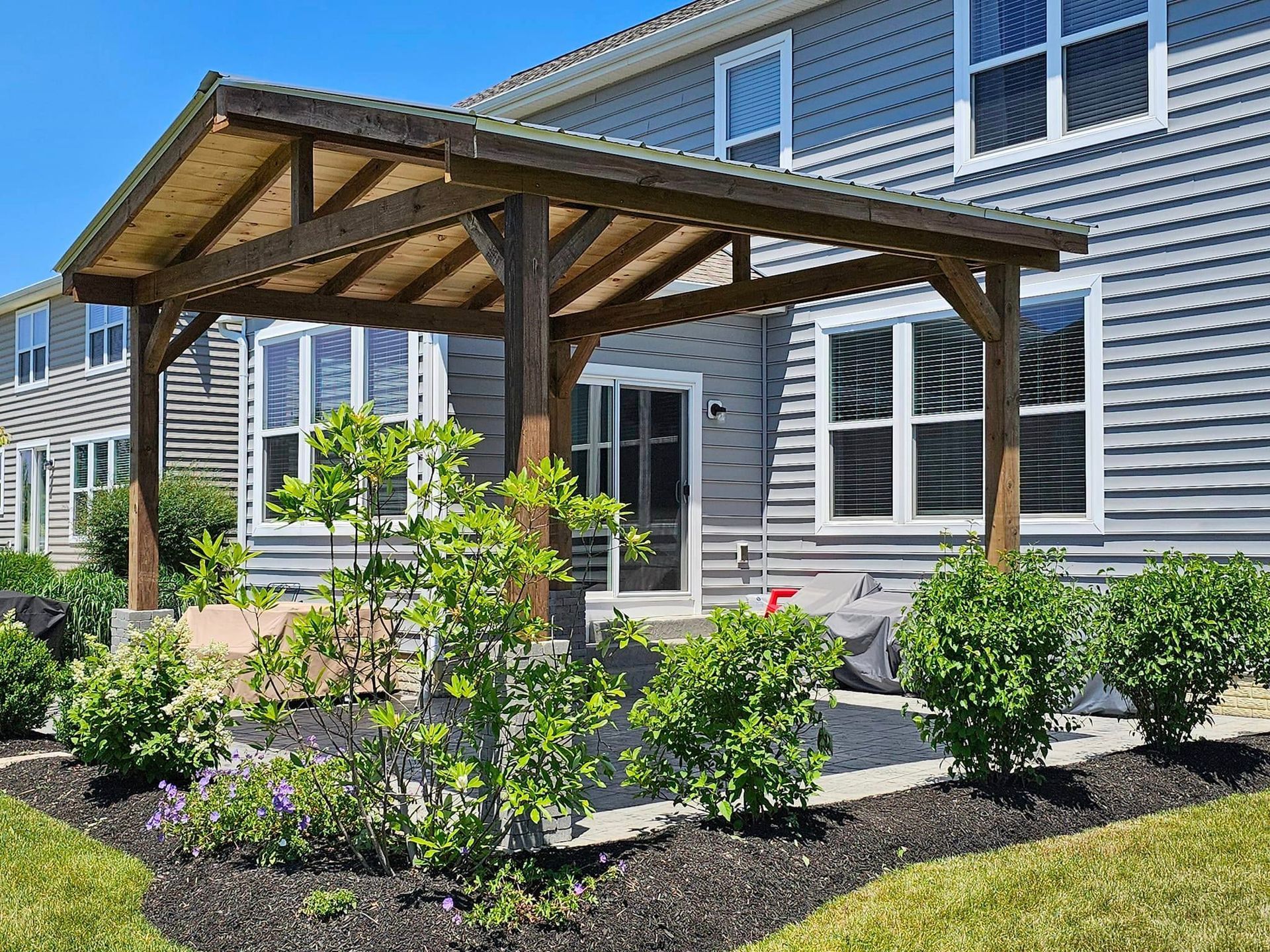 A large house with a wooden pergola in front of it.