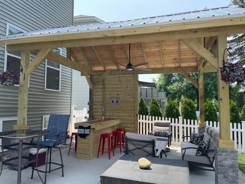 A wooden gazebo with a table and chairs underneath it