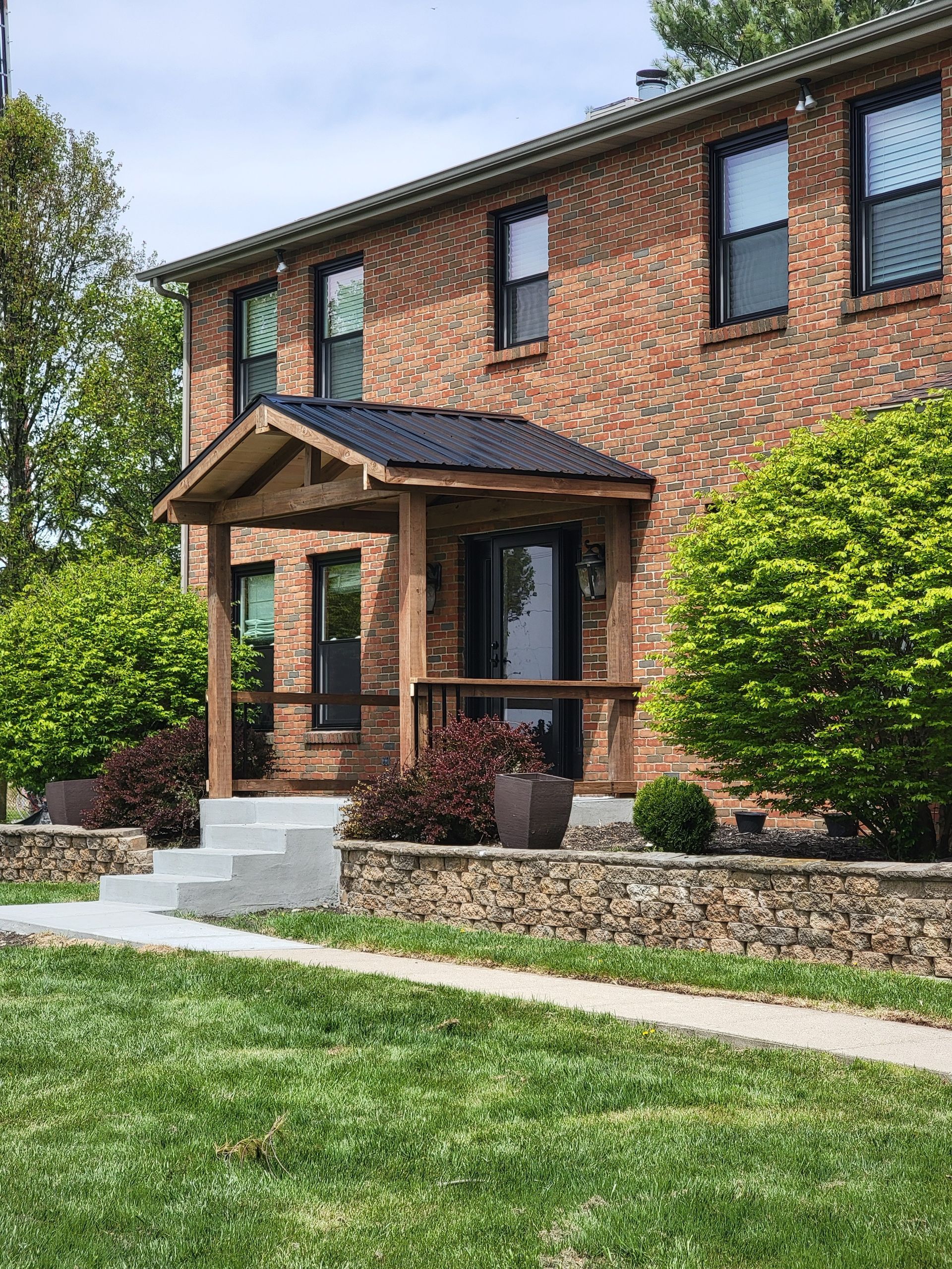 A brick house with a wooden porch and stairs in front of it.