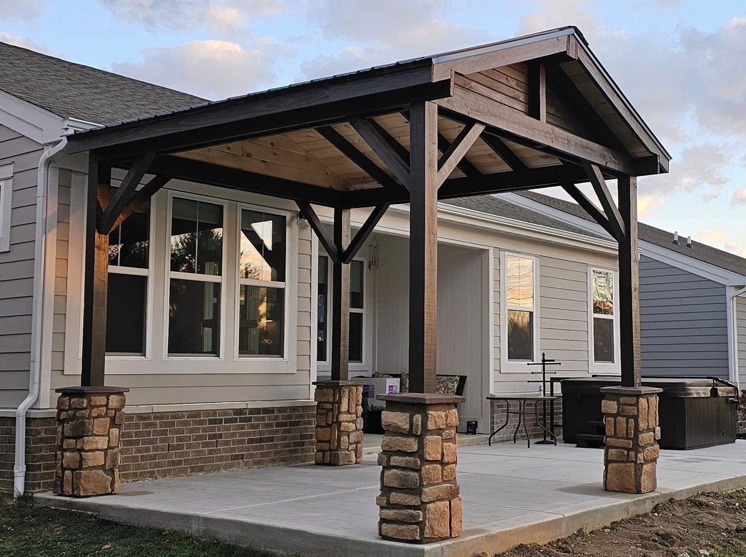A house with a wooden porch and stone pillars in front of it.