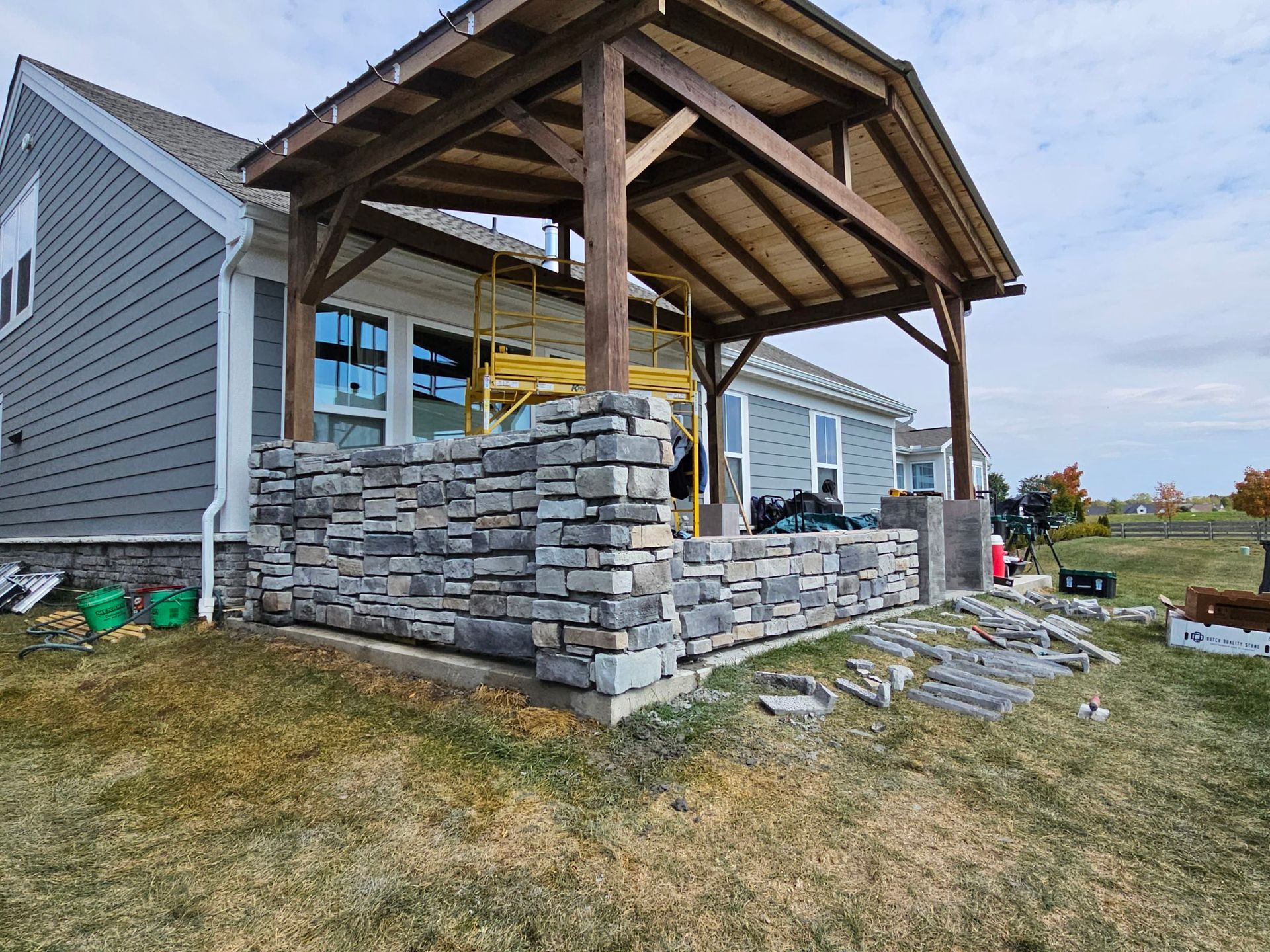 A stone wall is being built in front of a house.