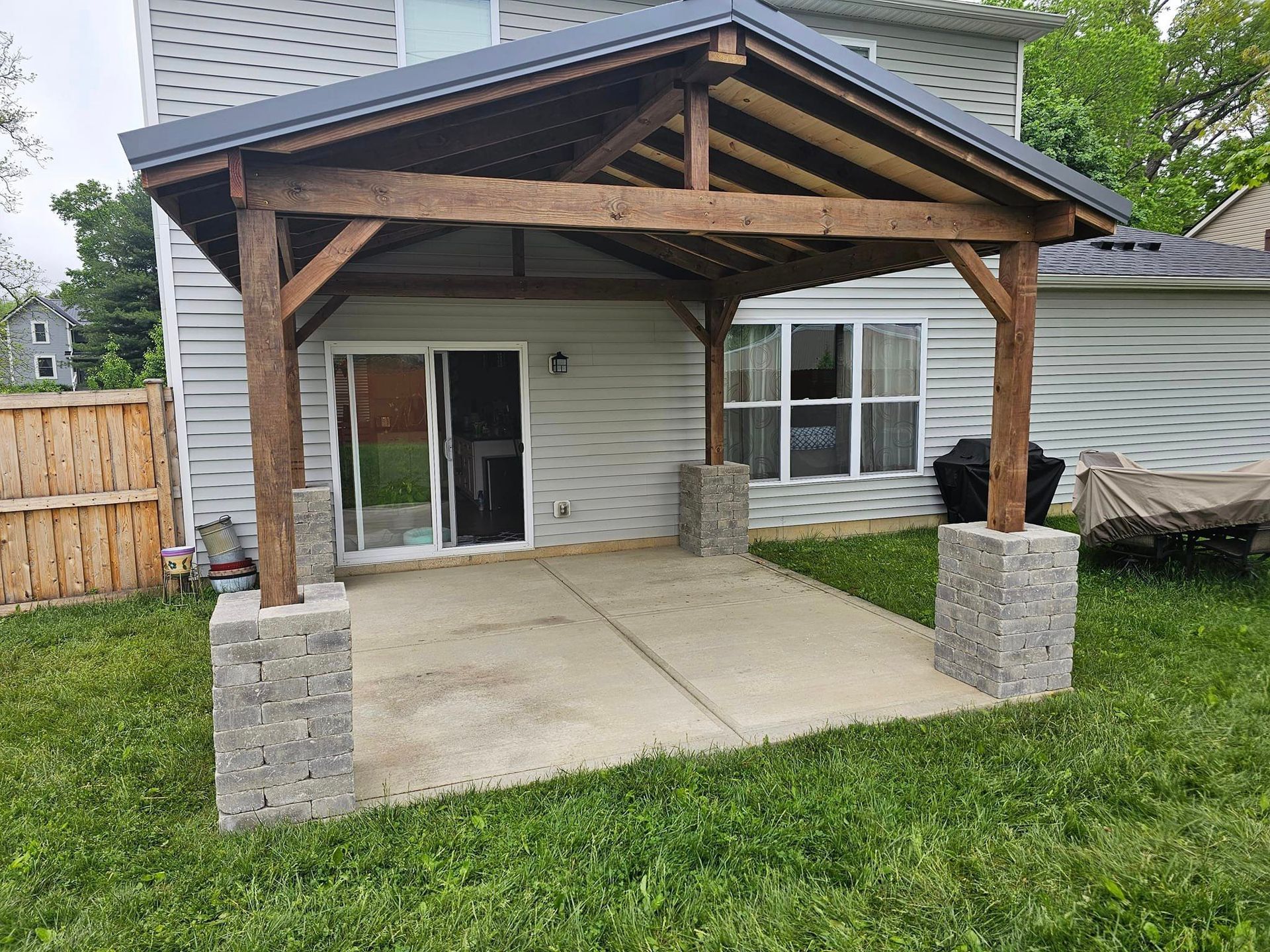 A wooden pergola is sitting in the backyard of a house.