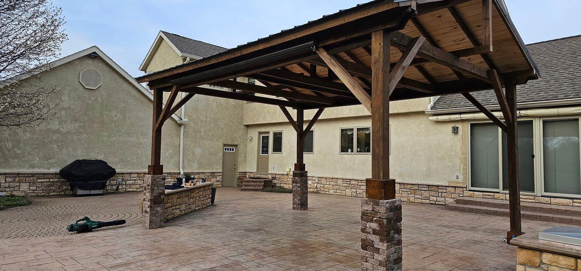 A large wooden gazebo is in the backyard of a house.