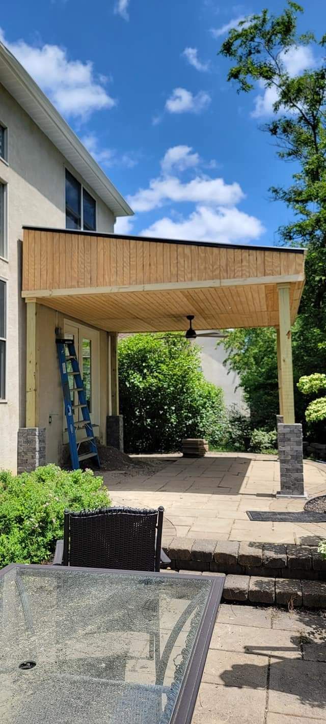 A wooden pergola is being built in the backyard of a house.