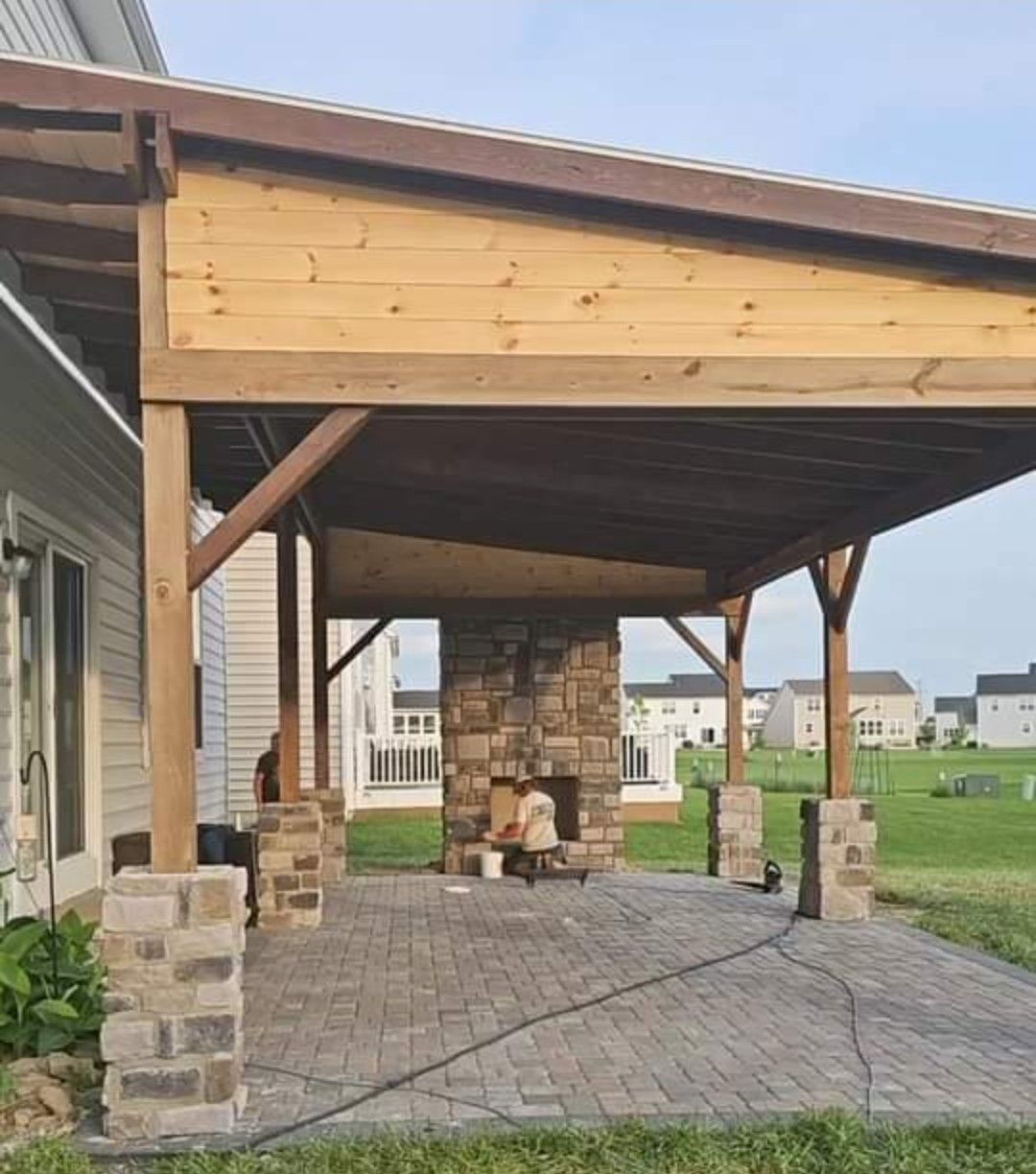 A wooden patio with a stone fireplace underneath it