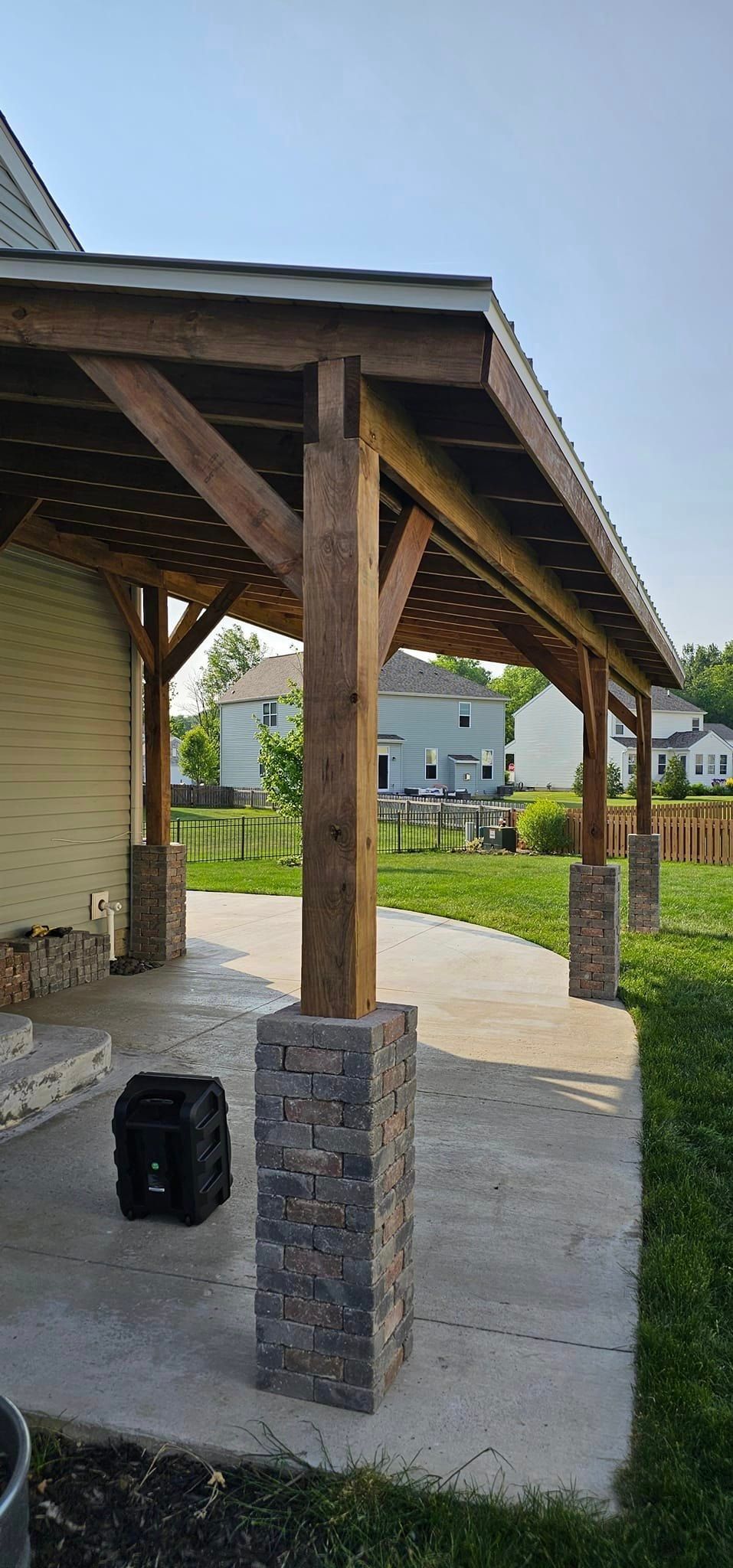 A wooden porch with a roof and pillars in front of a house.