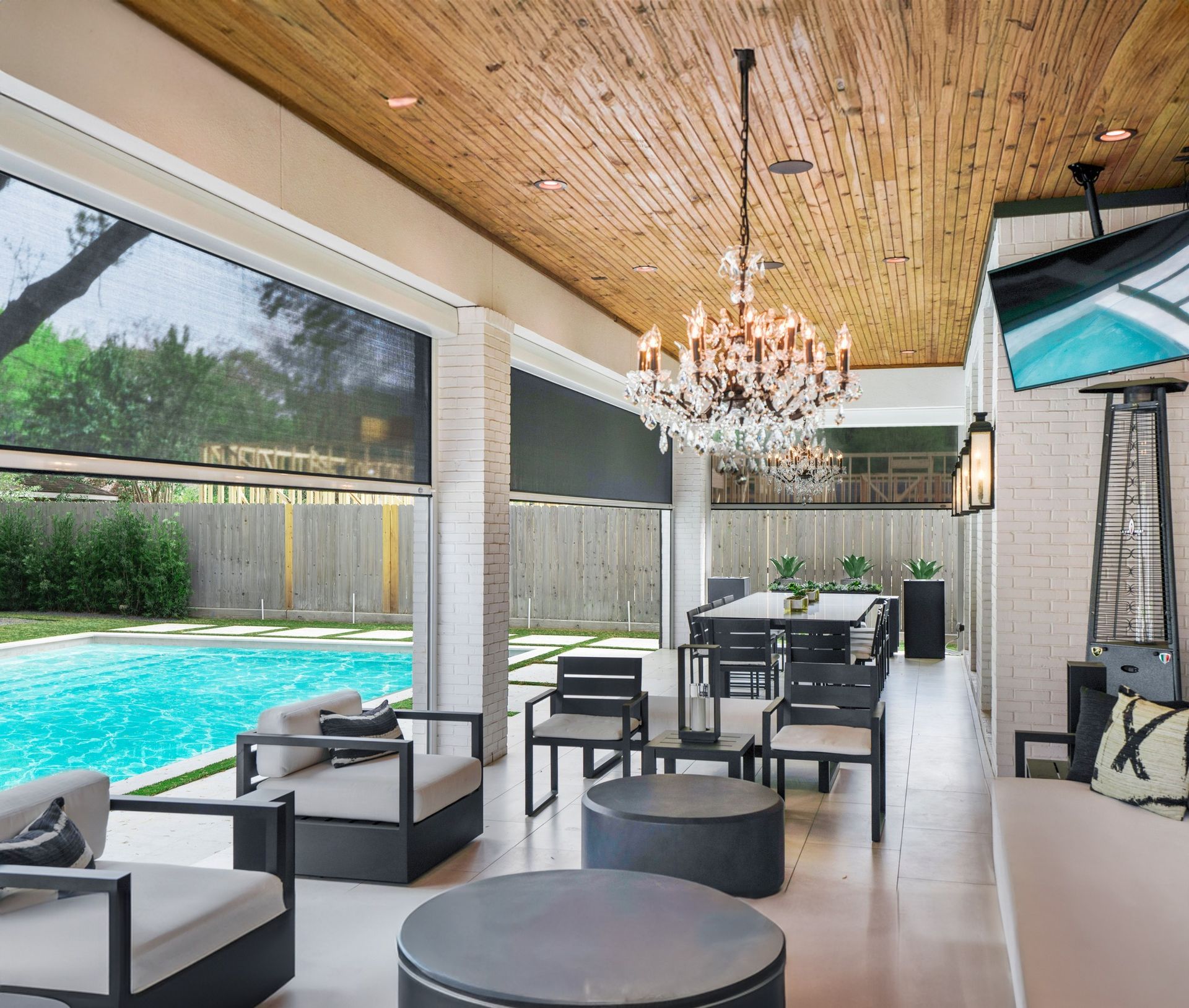 A living room with a swimming pool in the background and a chandelier hanging from the ceiling.