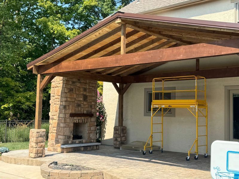 A wooden covered patio with a fireplace and a yellow scaffolding.
