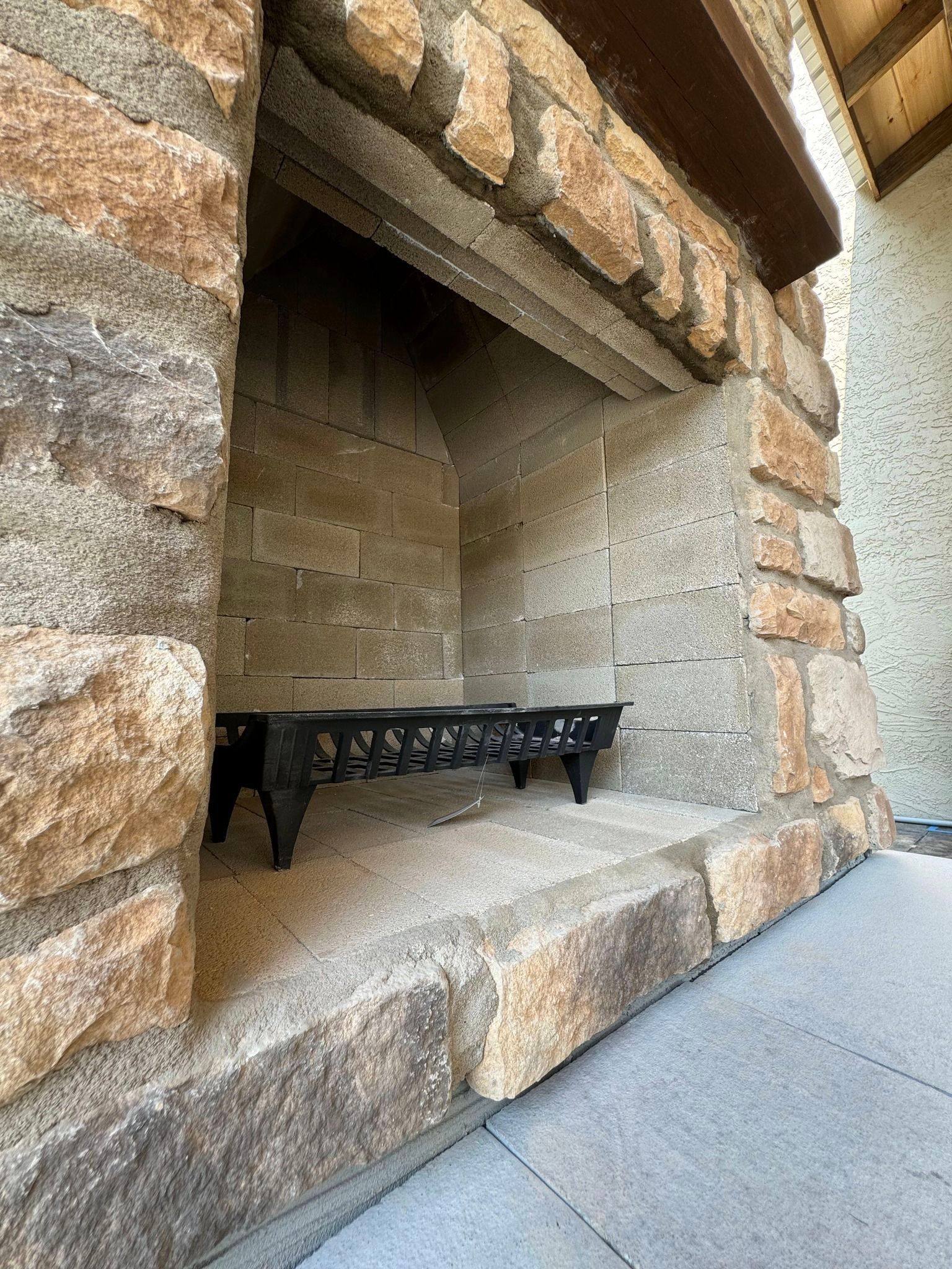 A stone fireplace with a metal grate in it.