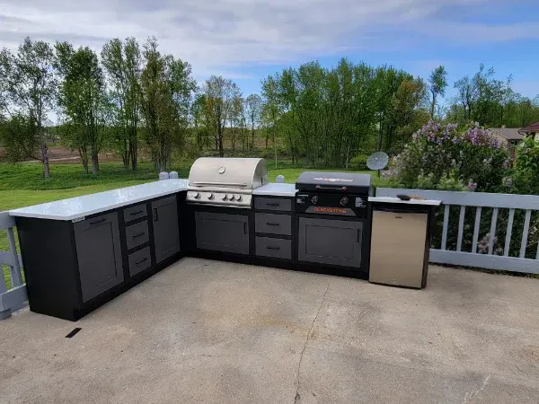 A large outdoor kitchen with a grill and a refrigerator