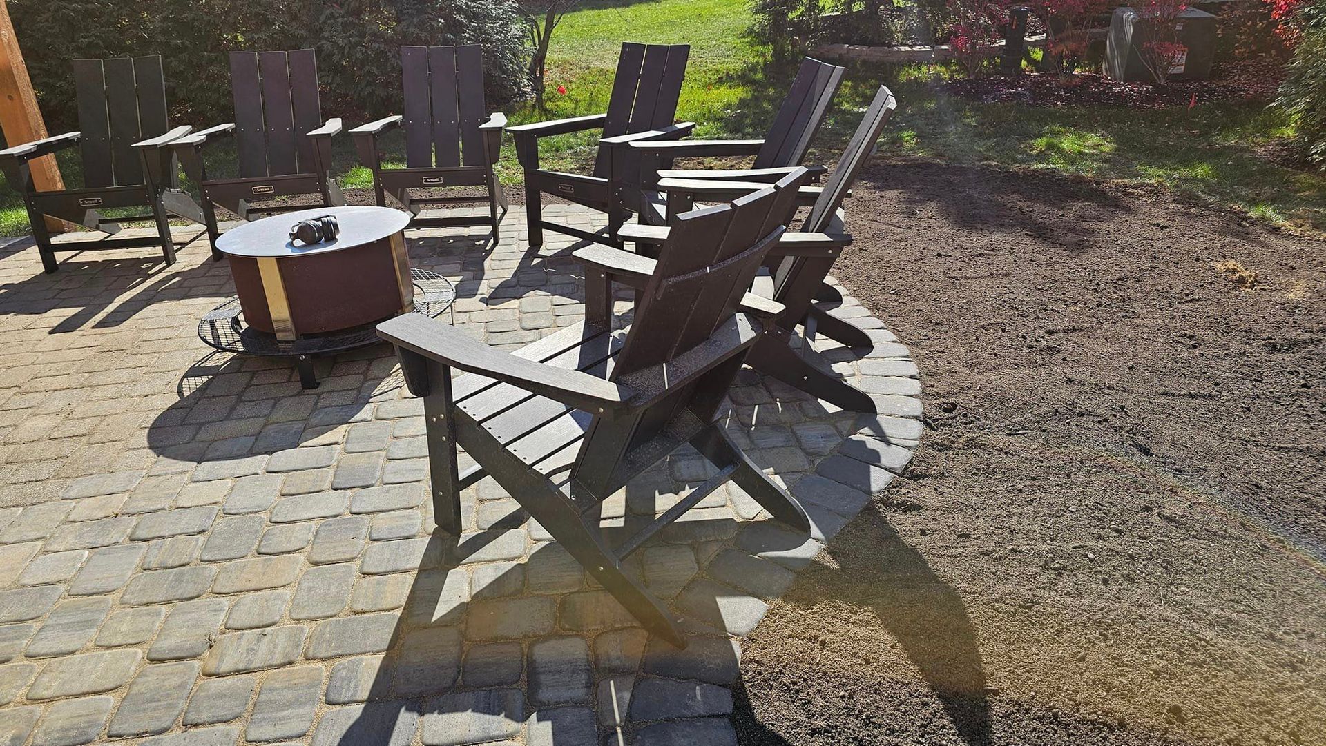 A group of chairs are sitting on a patio next to a fire pit.