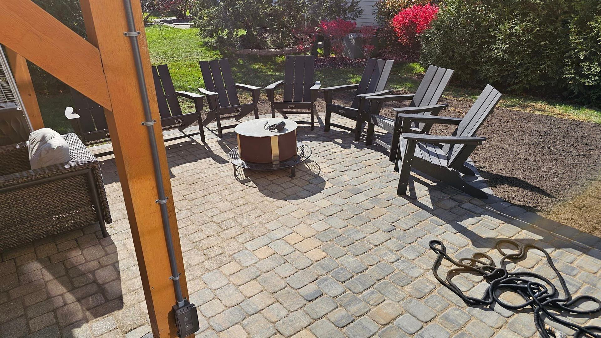 A patio with a fire pit and chairs on a sunny day.