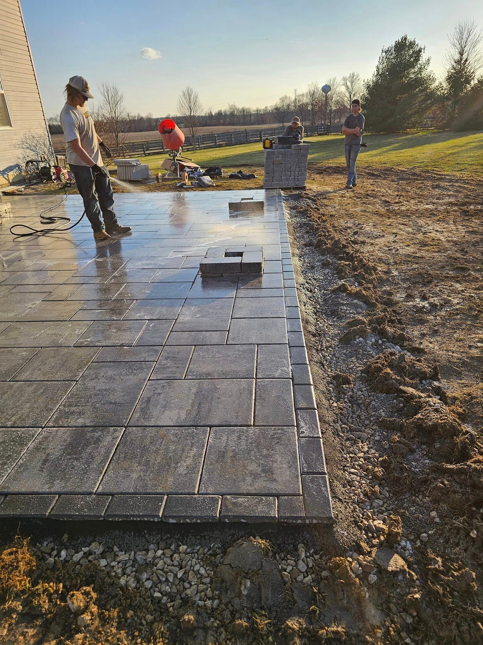 A couple of men are standing on top of a concrete patio.