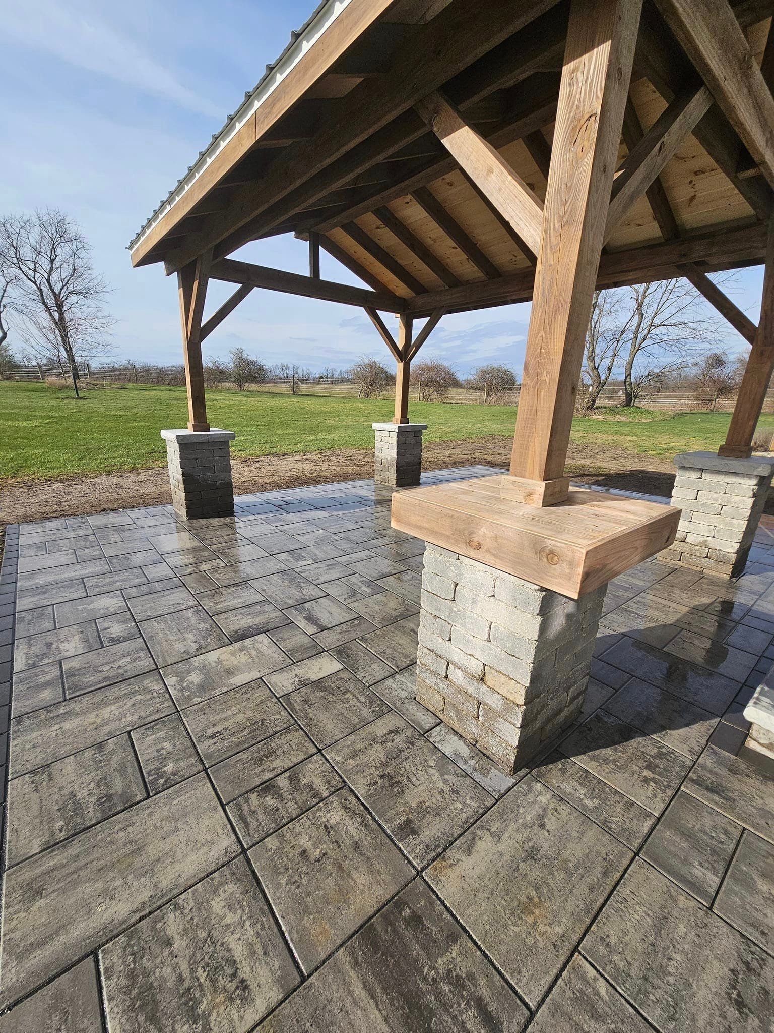 A wooden gazebo is sitting on top of a brick patio.