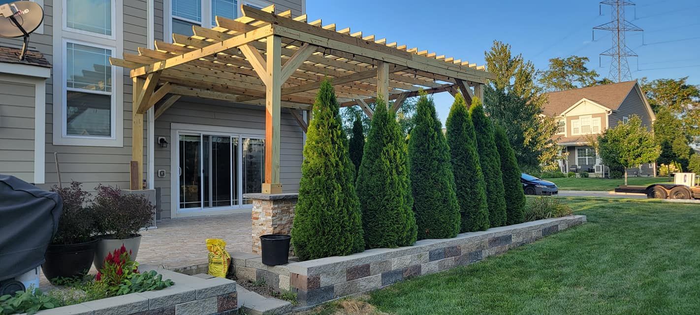 A house with a pergola and trees in front of it.