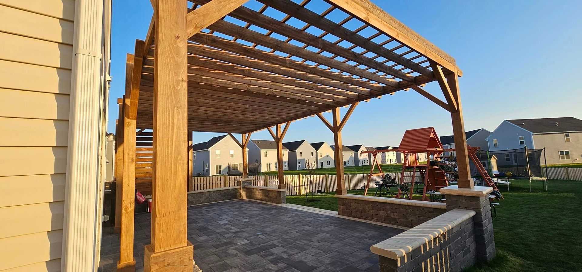 A wooden pergola is sitting in the backyard of a house.