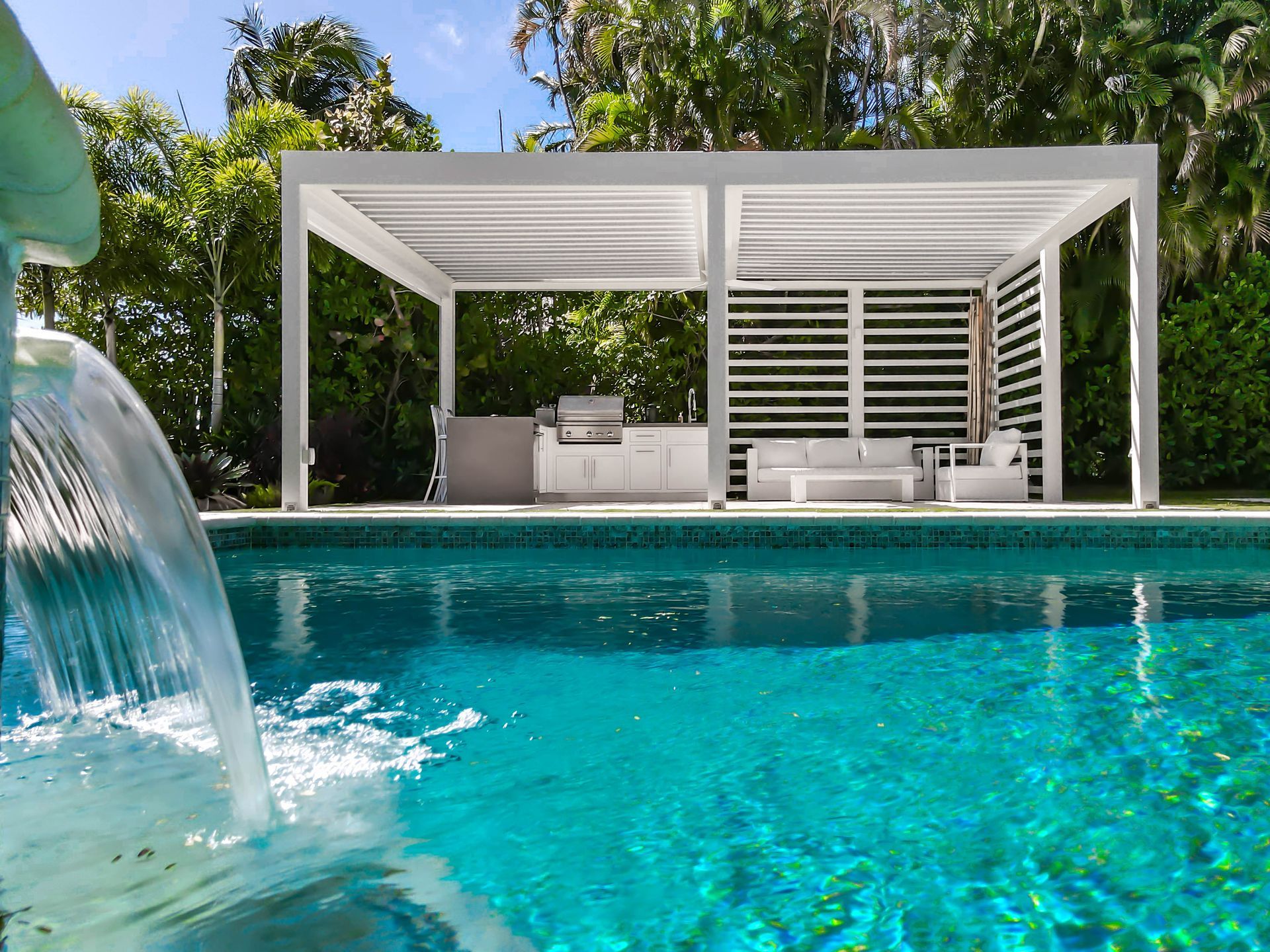 A swimming pool with a pergola and a waterfall in the background.