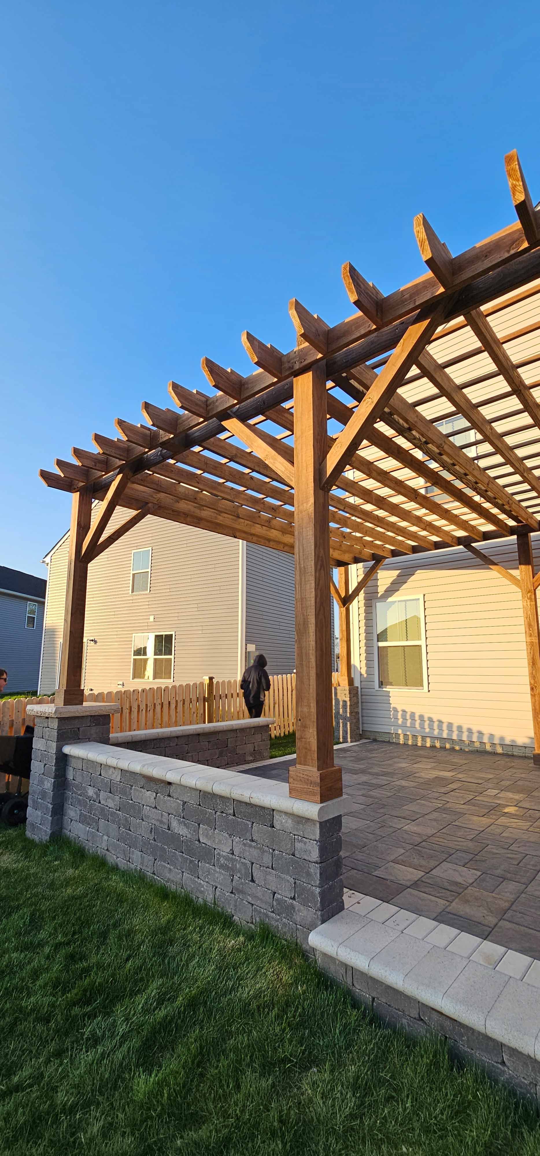 A wooden pergola is sitting in the backyard of a house.
