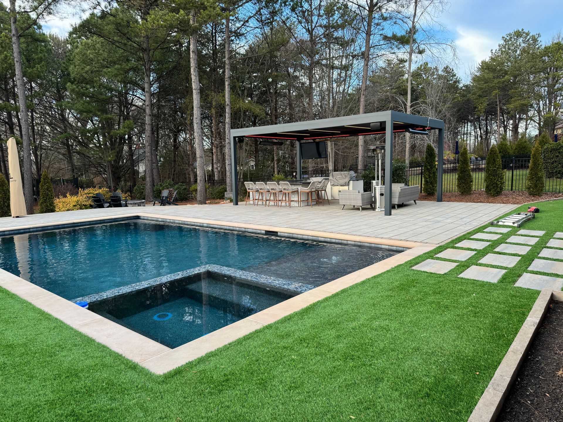 There is a large swimming pool in the middle of the backyard.