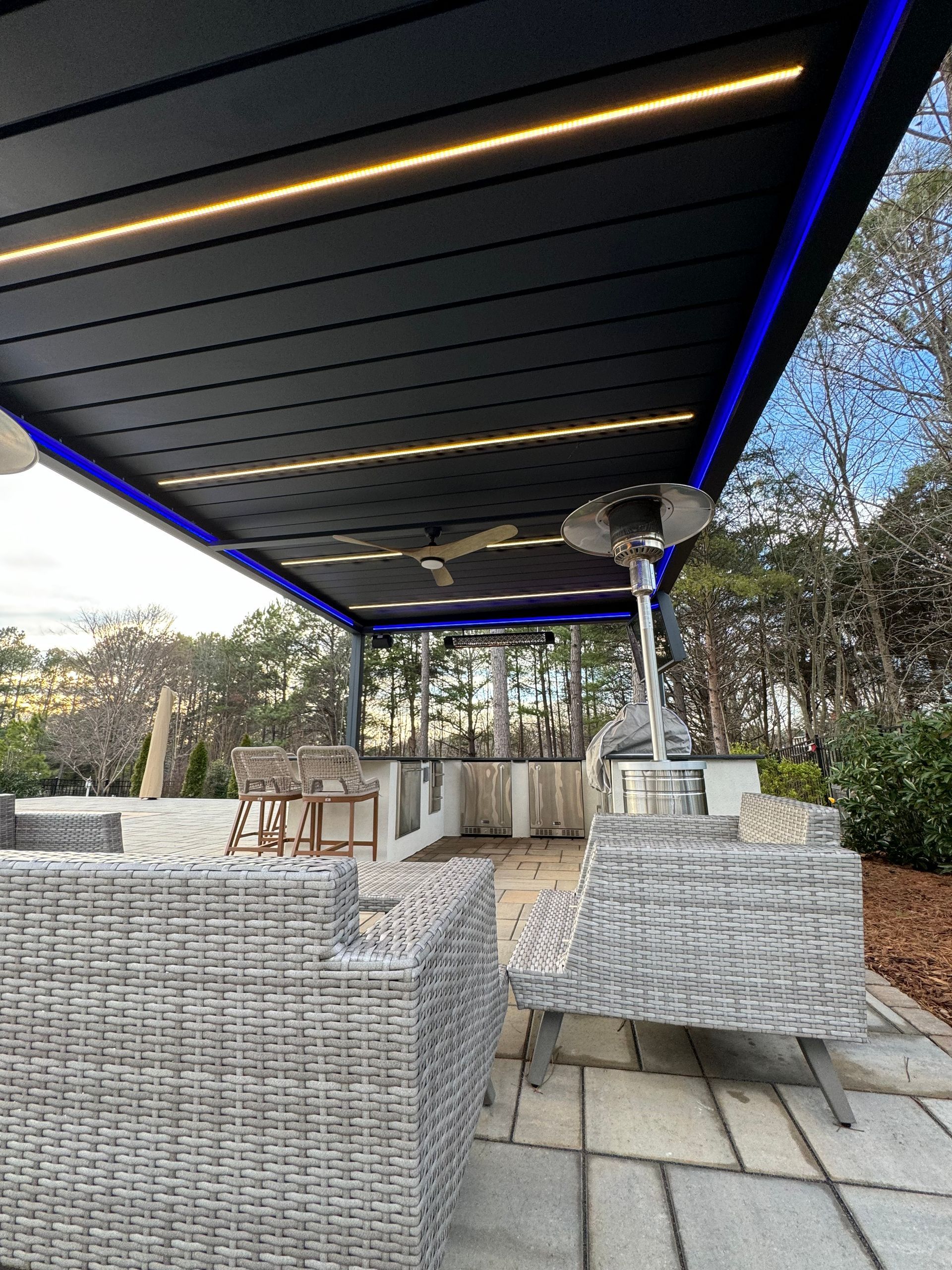 A patio with chairs and a heater under a pergola