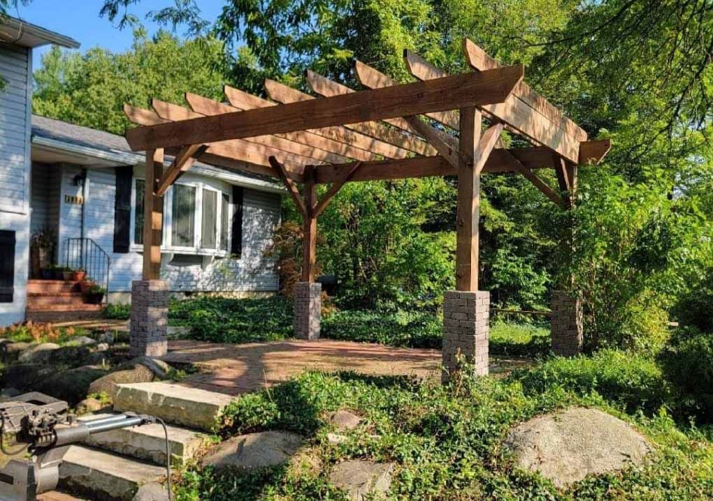 A wooden pergola is sitting in front of a house.