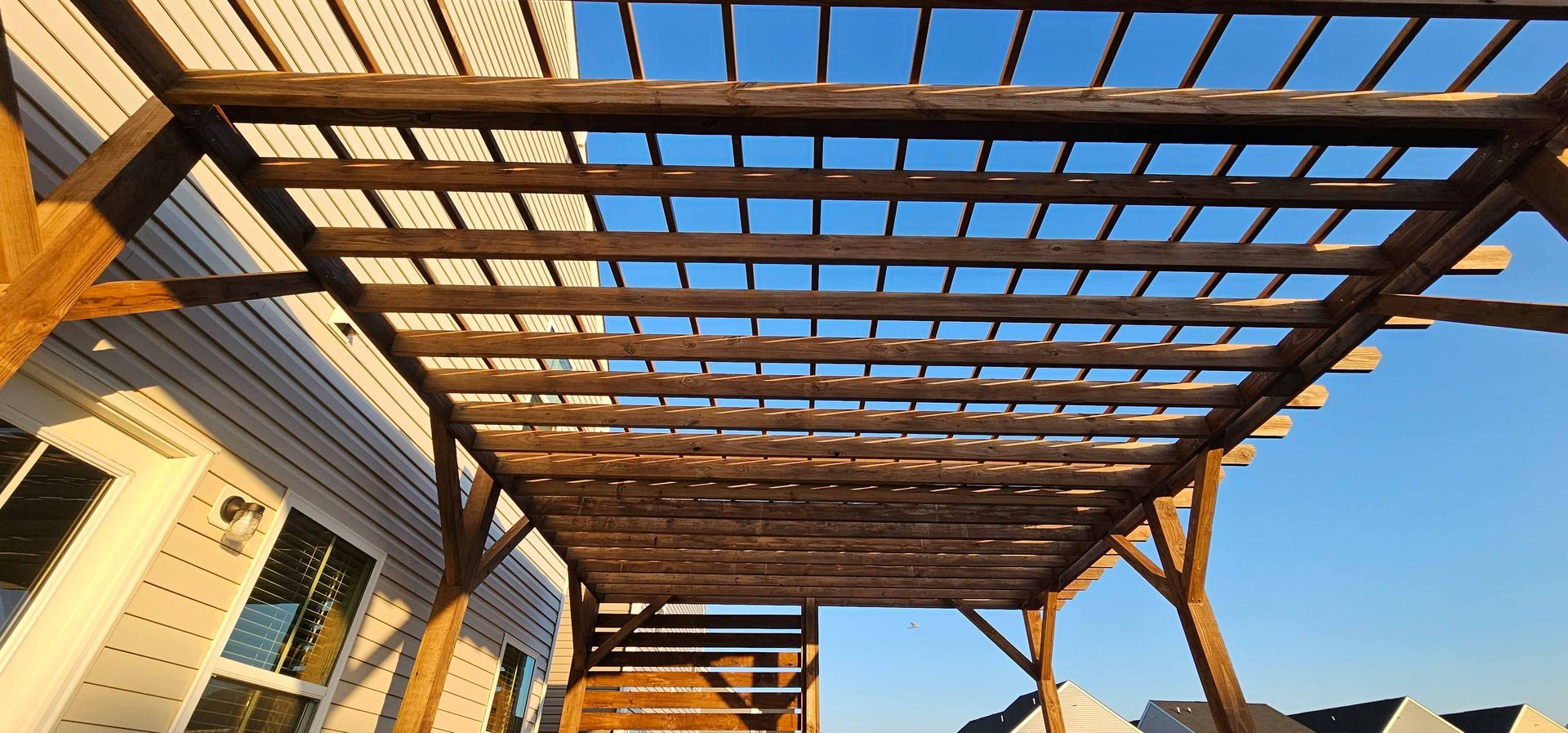 A wooden pergola is sitting in front of a house.