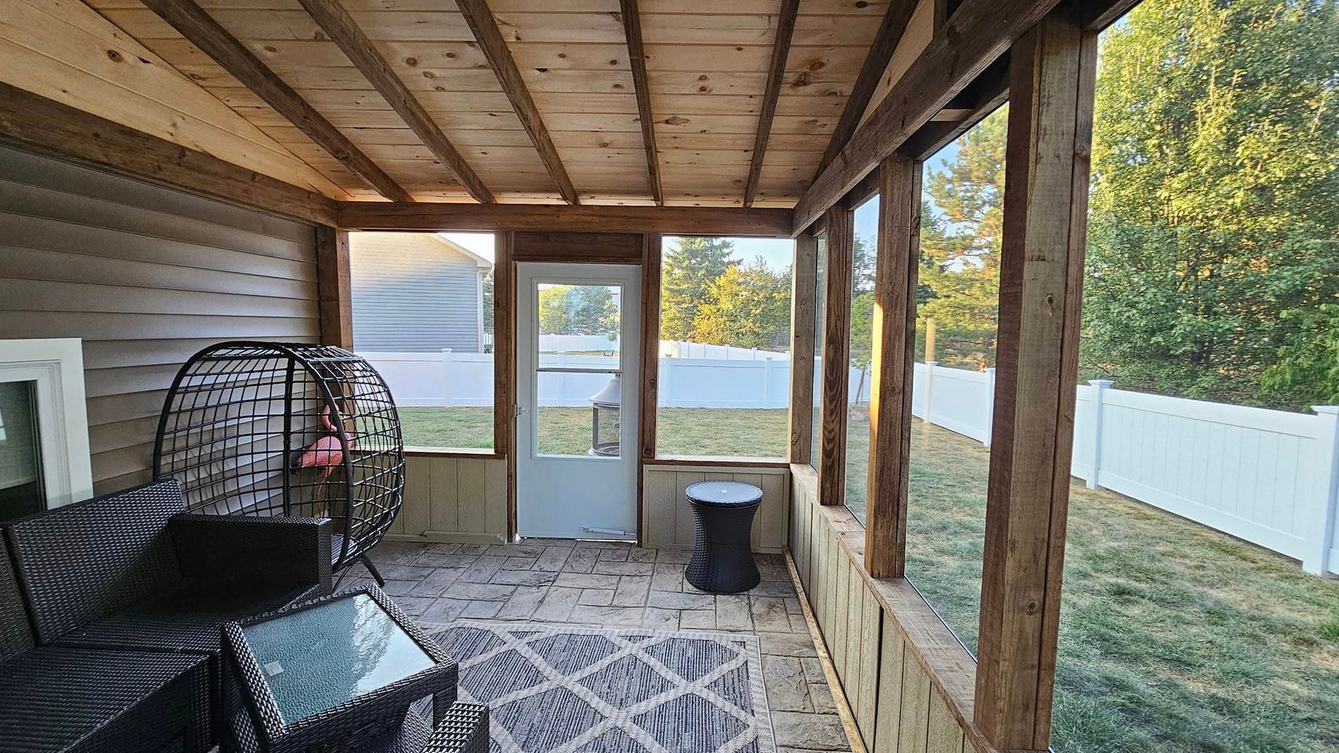 A screened in porch with a chair , table , and television.