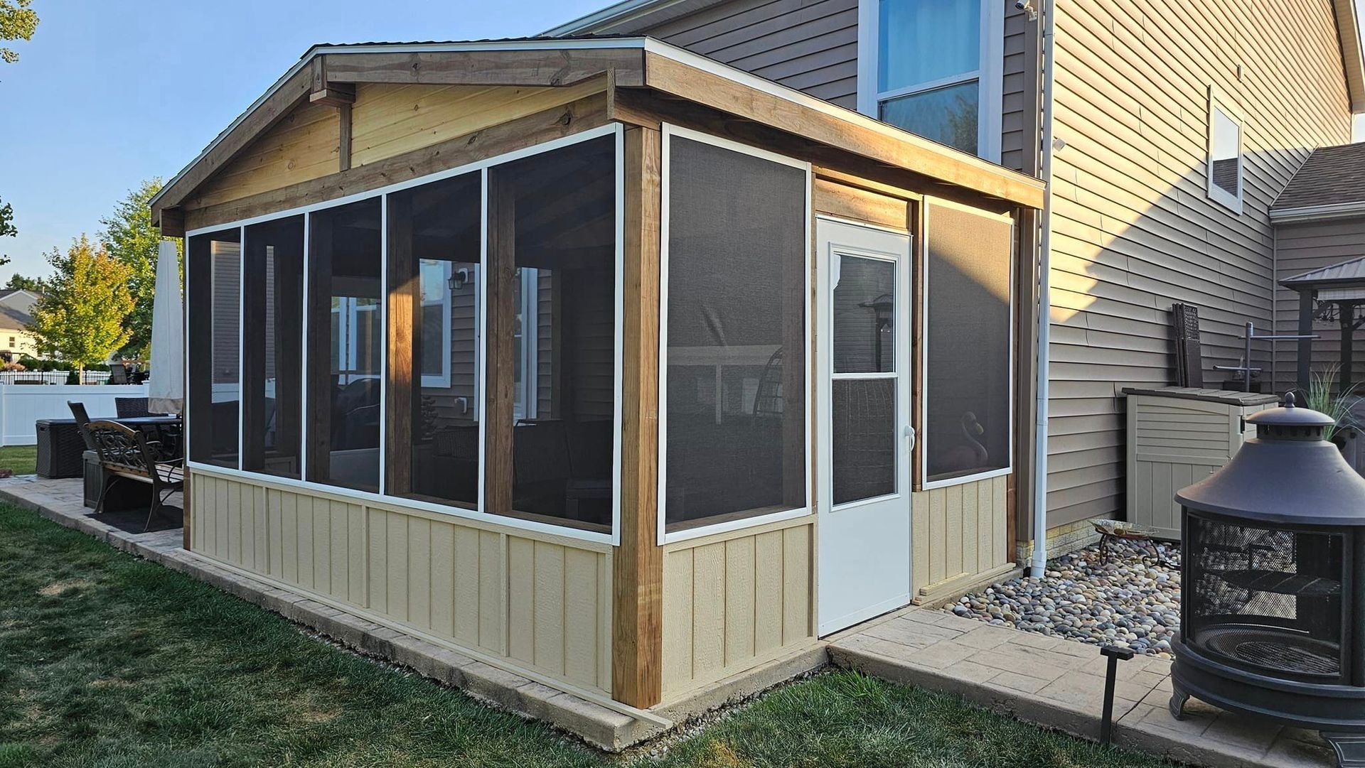 A screened in porch in the backyard of a house.