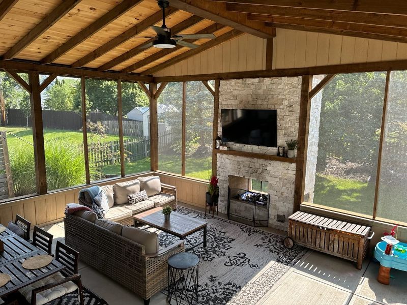 A screened in porch with a couch , table and television.