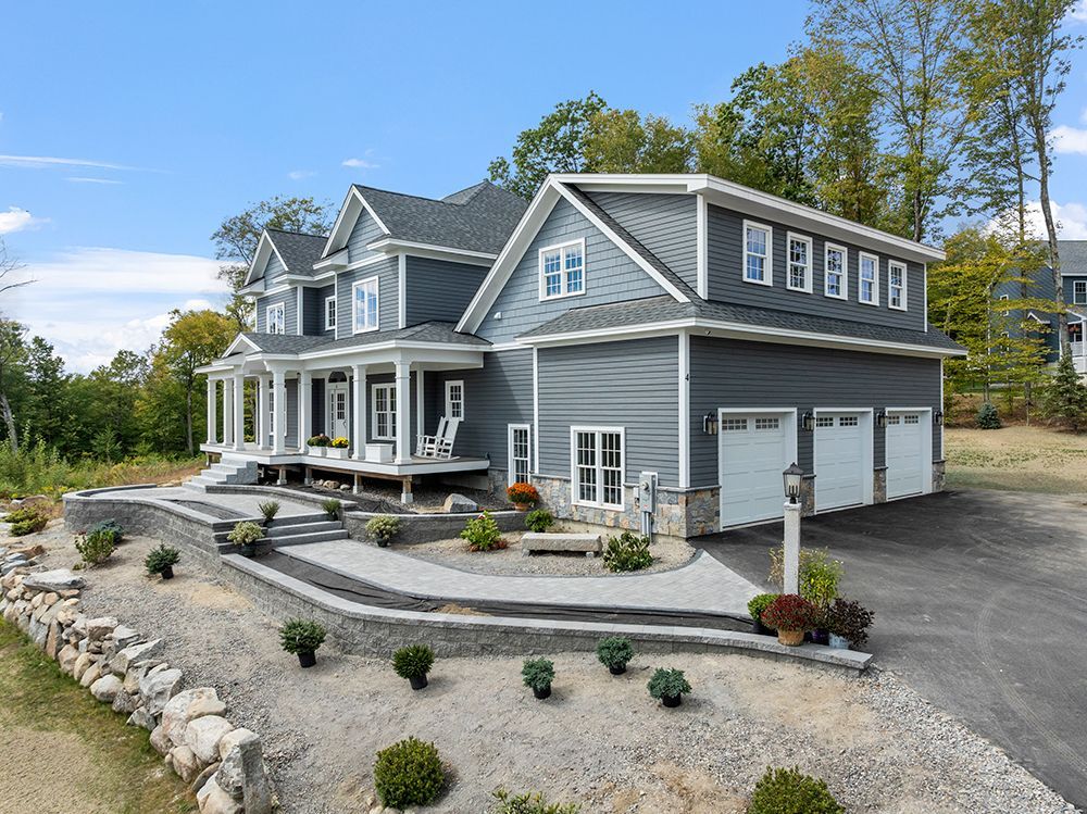 Gray house with white trim, three-car garage, porch, and landscaped yard.