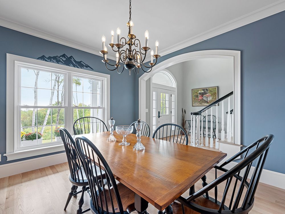 Dining room with blue walls, wooden table, black chairs, and a chandelier.