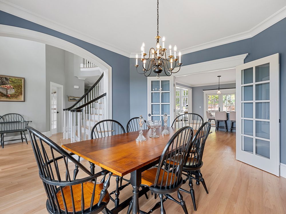 Dining room with wood table and chairs, blue walls, chandelier, hardwood floors, and French doors.