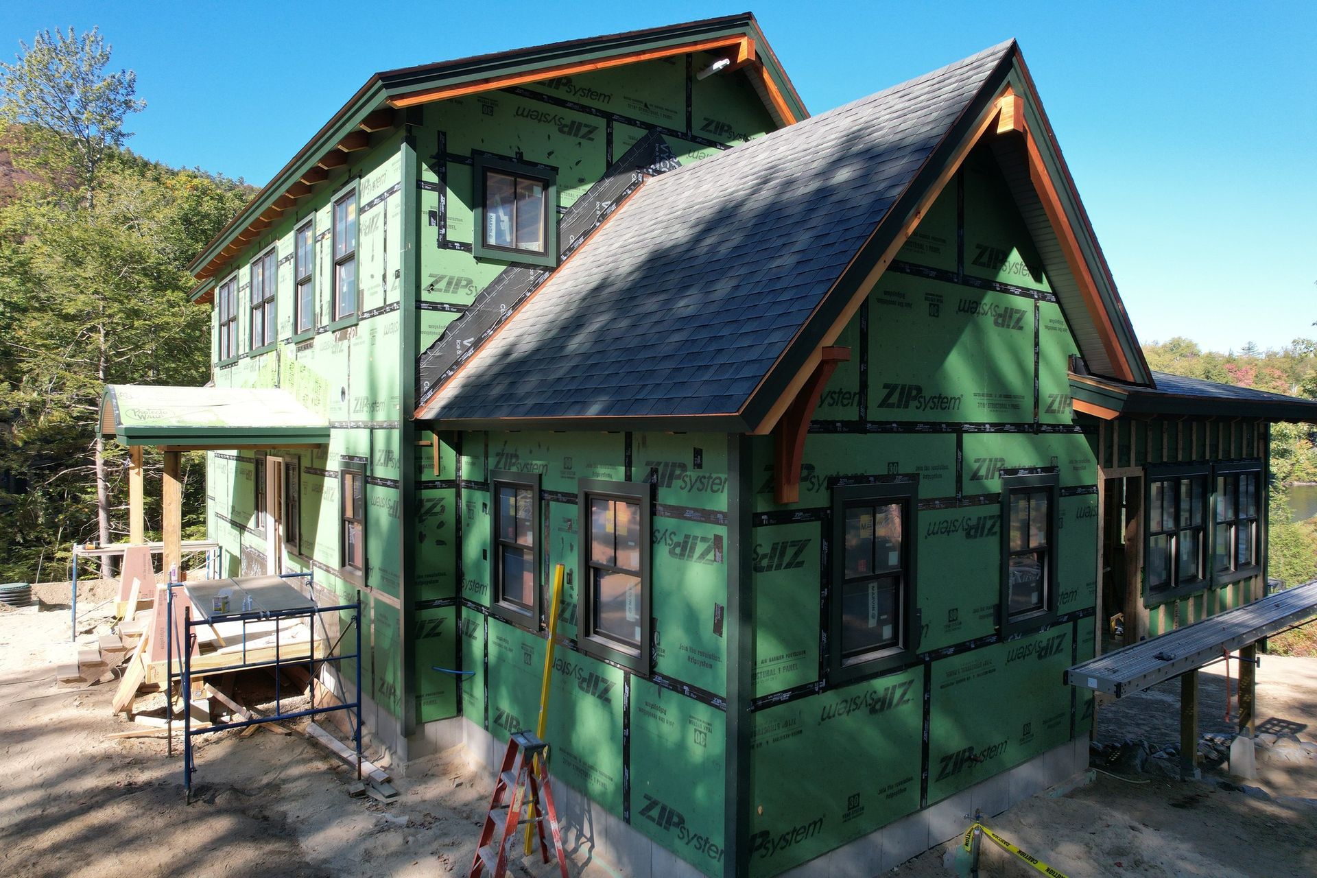 House under construction with green siding, dark windows, and a dark roof.