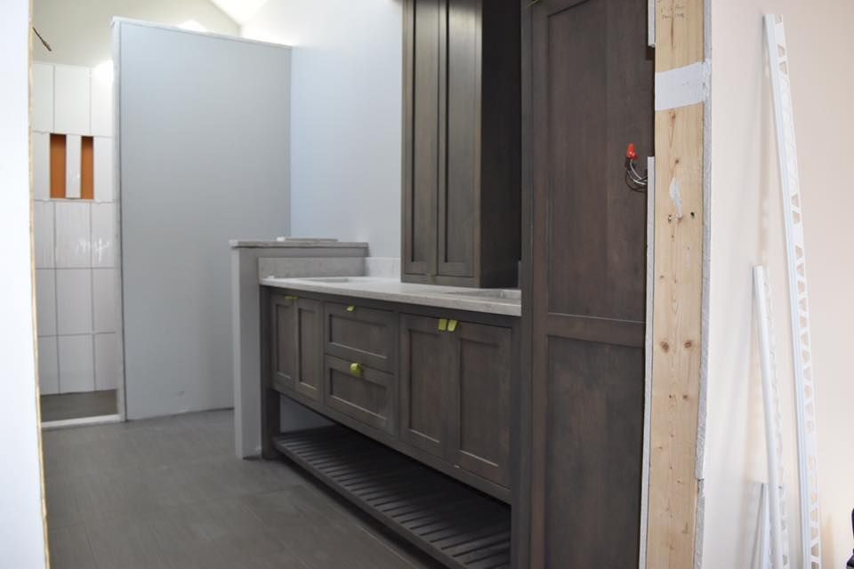 Bathroom with dark wooden vanity, built-in cabinet, gray countertop, and gray floor; unfinished walls.