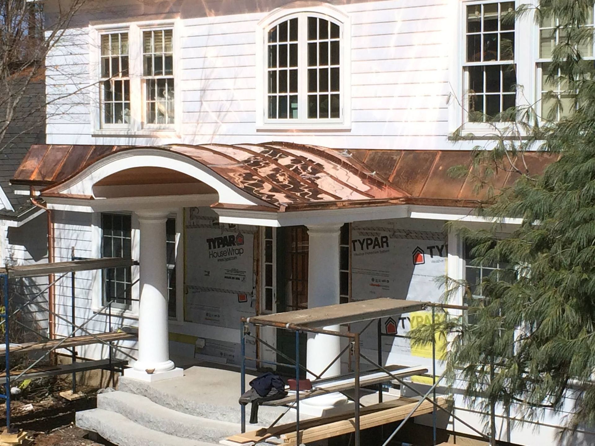 White house with copper awning and porch under construction.