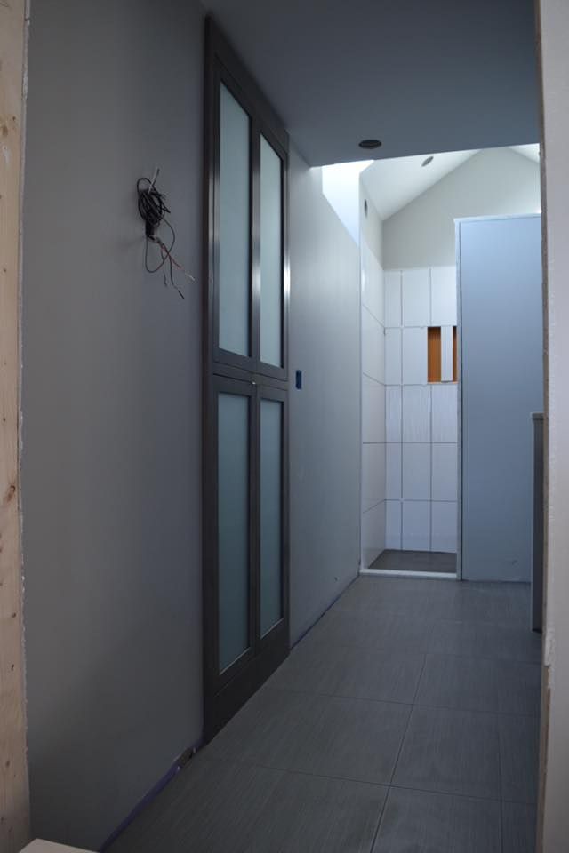 Gray hallway with a sliding frosted glass door, leading to a shower area.
