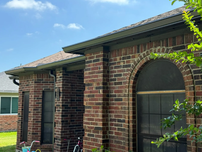 Brick building with dark gutters and a large arched window against a blue sky.