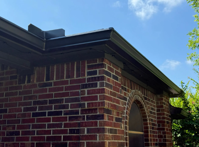 Brick building corner with dark gutters against a blue sky.