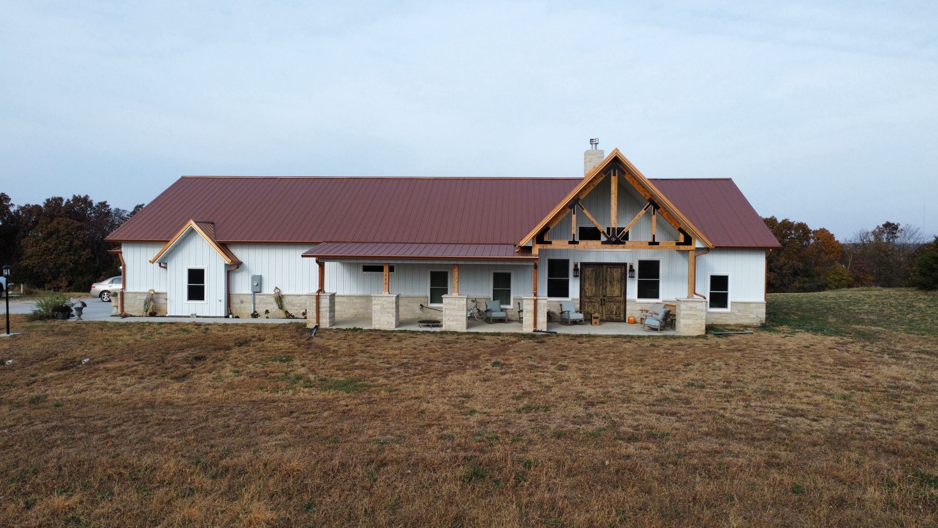 A white house with a red roof under construction, on a brown field.