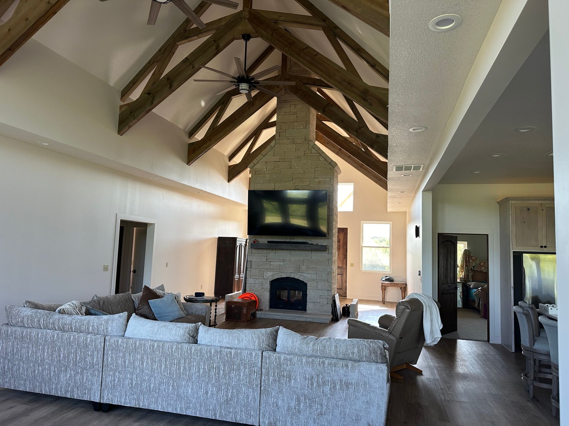 Living room with vaulted ceiling, fireplace, large sectional sofa, and exposed wooden beams.