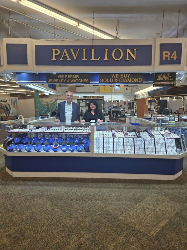 A jewelry store kiosk with two people behind display cases of jewelry. Sign says 