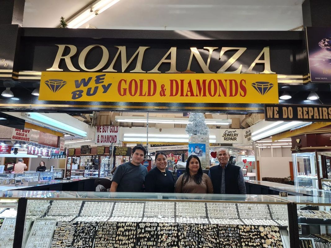 People behind jewelry display, storefront sign reads 