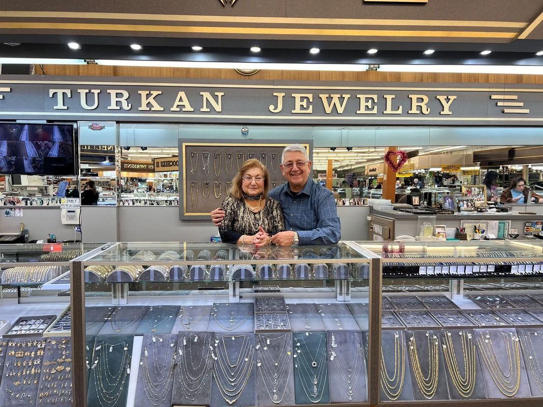 Couple standing behind a jewelry display counter at Turkan Jewelry store.
