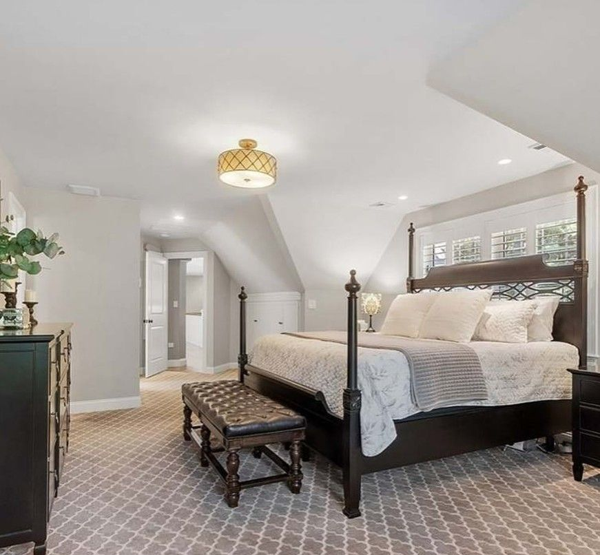 Bedroom with a four-poster bed, patterned carpet, and black furniture.