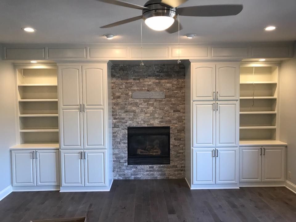 Living room with fireplace and built-in white cabinets with shelving and recessed lighting.