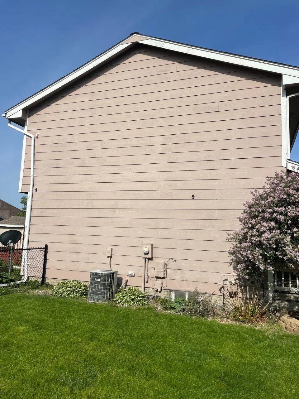 Tan house exterior with air conditioning unit and green grass.