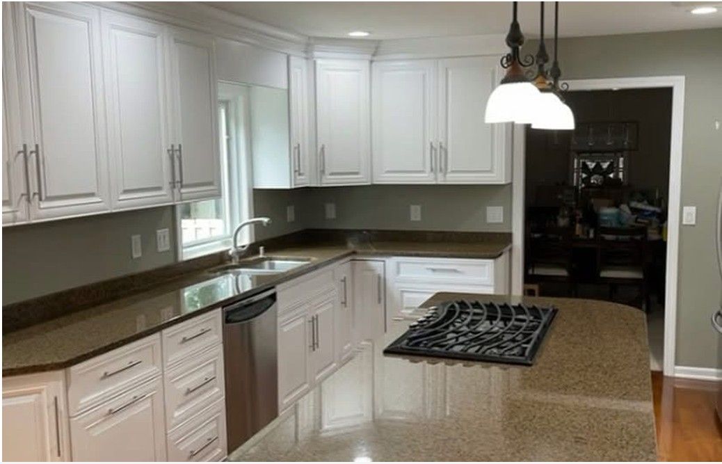 White kitchen with granite countertops, stainless steel appliances, and a stove-top island.