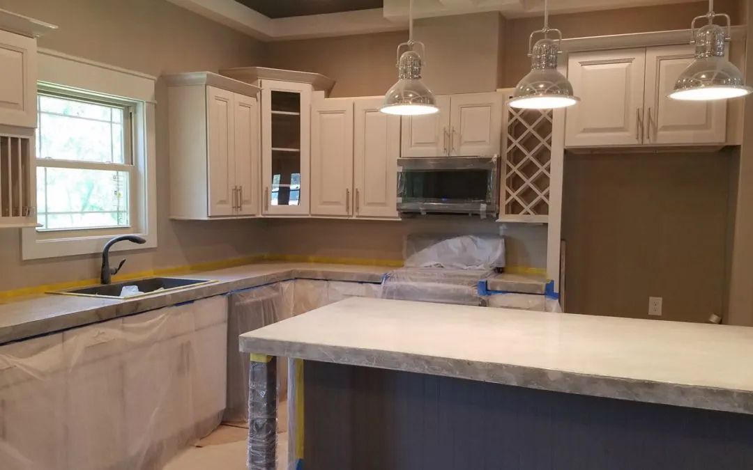 Kitchen with white cabinets, gray countertops, and three pendant lights.