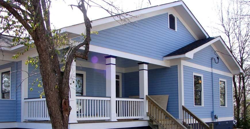 Blue house with white trim, porch, and stairs. Tree in front.