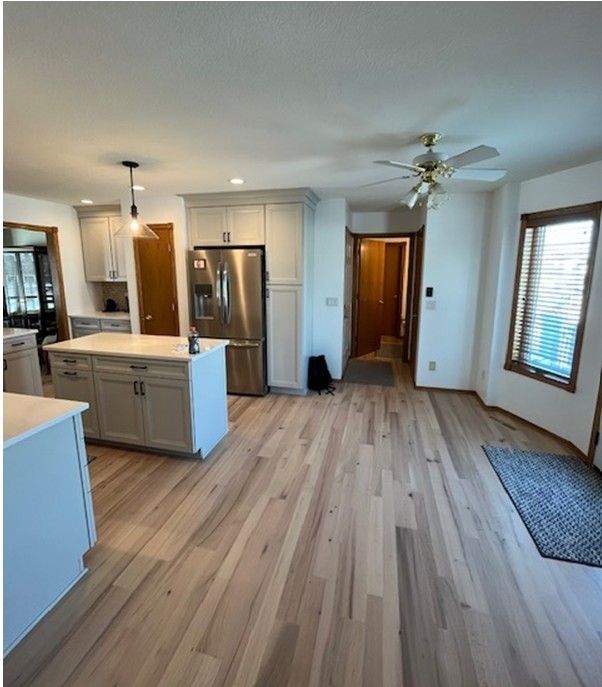Kitchen with light wood floor, gray cabinets, stainless steel appliances, and a central island.